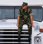 Person in army fatigues sitting on bus hood
